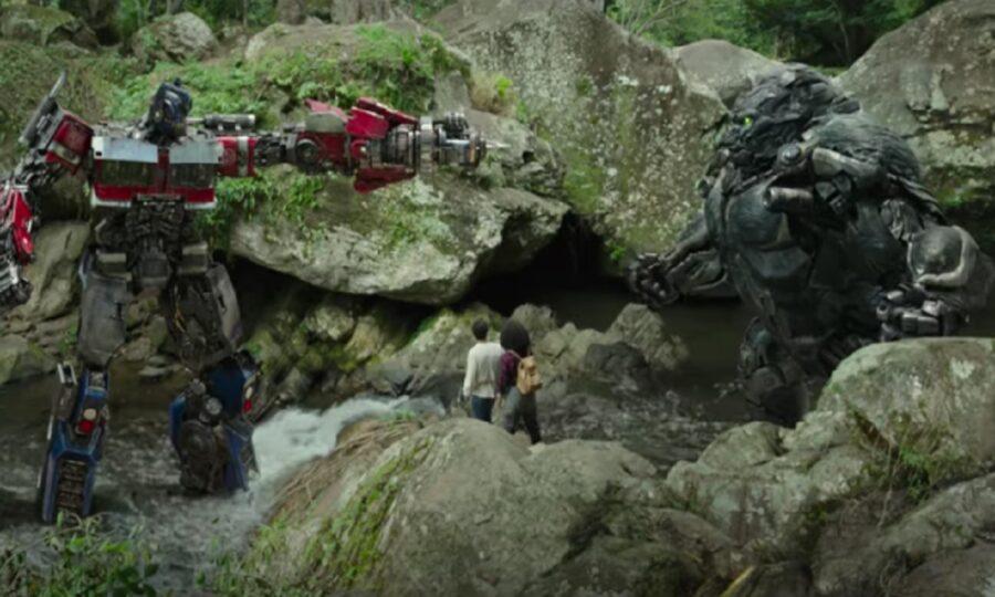 Optimus Prime and Optimus Primal face off in a forest.